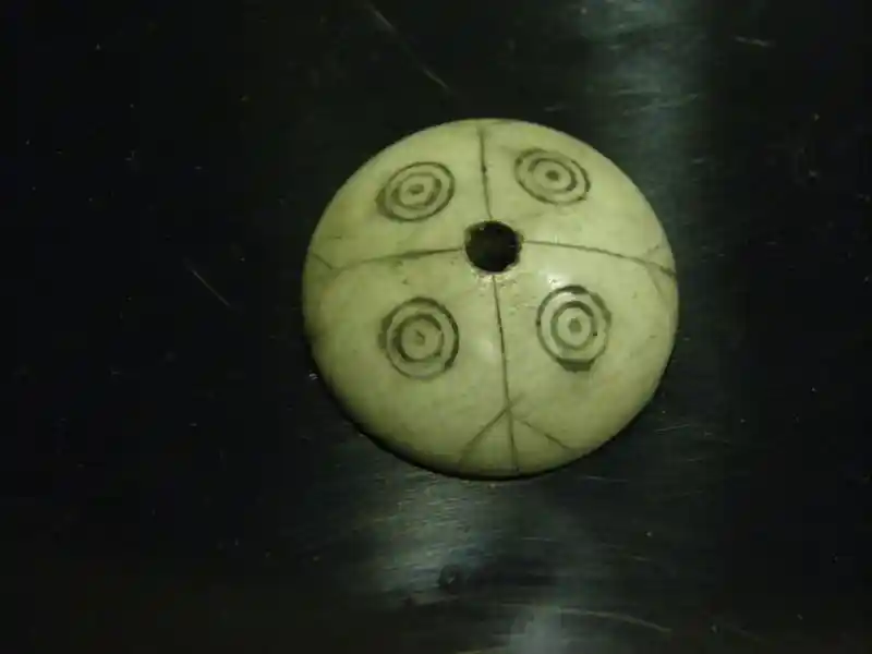 Solar disc with four solar symbols and a cross and a hole in the center